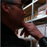 Charles consulte un rayon de bibliothèque rempli de ses livres d'occasion