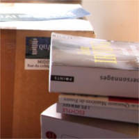 Une pile de livres d'occasion posée devant un colis prêt à partir